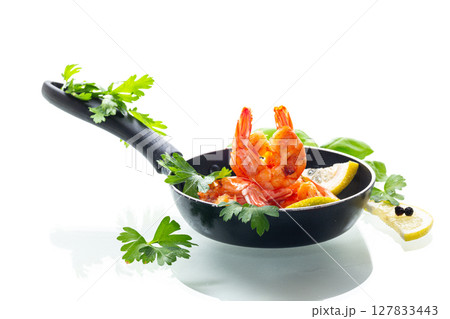 Hot shrimps with citrus slices and spices in a frying pan isolated on white 127833443