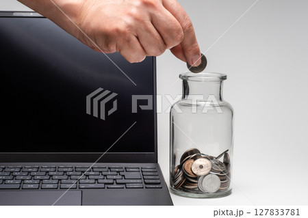 パソコンの横のガラス瓶にお金を入れて副業のイメージ 127833781