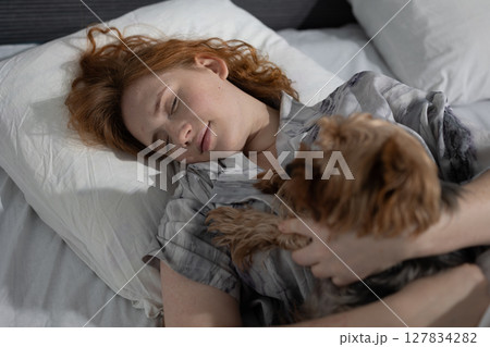 Young Woman Peacefully Sleeping With Her Small Dog in a Cozy Bedroom Setting Young Woman Peacefully Sleeping With Her Small Dog in a Cozy Bedroom Setting 127834282