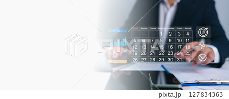 Person interacting with a digital calendar overlay, planning business tasks with icons for growth, gears, targets, and checkmarks, Efficient scheduling, strategic project management, goal achievement. Person interacting with a digital calendar overlay, planning business tasks with icons for growth, gears, targets, and checkmarks, Efficient scheduling, strategic project management, goal achievement. 127834363
