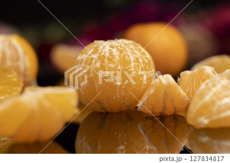 the reflection of an orange tangerine in a mirror surface close up, a peeled and juicy tangerine on a mirror 127834817