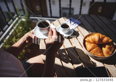 A serene morning setting featuring coffee and croissants on a wooden table. Ideal for enjoying a peaceful start to the day in a natural and fresh environment. 127835848