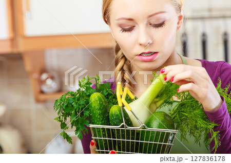 Woman in kitchen having vegetables holding shopping basket Woman in kitchen having vegetables holding shopping basket 127836178