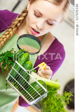 Woman looking through magnifier at vegetables basket 127836180