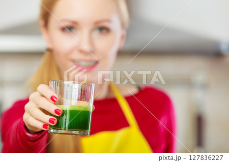 Woman in kitchen holding vegetable smoothie juice Woman in kitchen holding vegetable smoothie juice 127836227