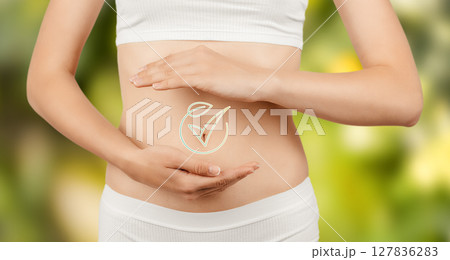 A healthy woman gently cradles her stomach, symbolizing wellness, digestion, and natural care with a glowing gut health icon on a green background 127836283