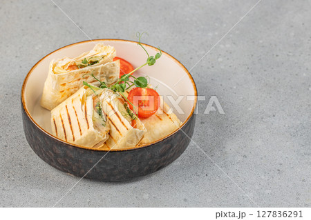 Grilled tortilla wraps filled with fresh vegetables and herbs served in a modern bowl with cherry tomatoes and microgreens Grilled tortilla wraps filled with fresh vegetables and herbs served in a modern bowl with cherry tomatoes and microgreens 127836291