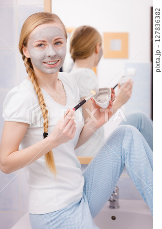 Woman with grey clay mud mask on her face Woman with grey clay mud mask on her face 127836382