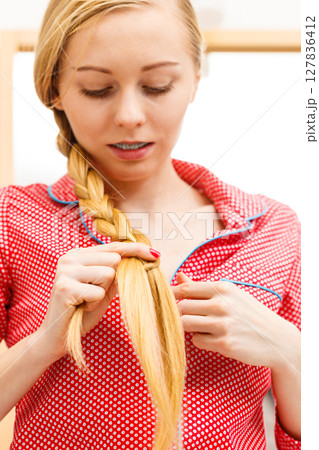 Woman doing braid on blonde hair 127836412