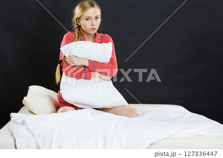 Sad depressed girl in bed gripping pillow Sad depressed girl in bed gripping pillow 127836447