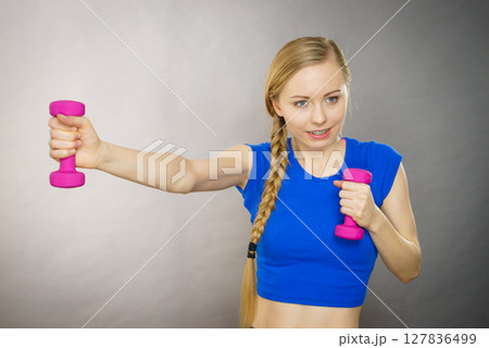 Teenage woman working out at home with dumbbell Teenage woman working out at home with dumbbell 127836499