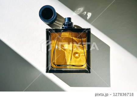 A golden bottle of perfume in a sunbeam. 127836718