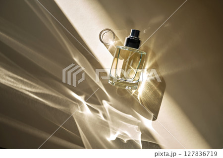 A beautiful perfume bottle on a beige background with beautiful reflected rays. 127836719