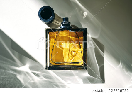 A golden bottle of perfume in a sunbeam. 127836720