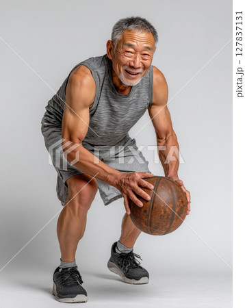 Senior Asian man demonstrating impressive basketball skills indoors Senior Asian man demonstrating impressive basketball skills indoors 127837131