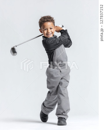 Middle Eastern boy joyfully swings golf club while practicing on a sunny day 127837152
