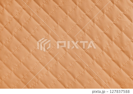 Checkered, diamond stitching pattern, orange quilted fabric background. Blanket stitch texture 127837588