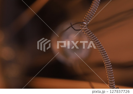 Tungsten filament, an incandescent light bulb, macro view, Metal texture in macro, silver wire 127837726