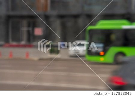 Blurred defocus background with cityscape of multi-lane road with moving vehicles such as green bus, white and black cars with motion blur. Soft focus 127838045