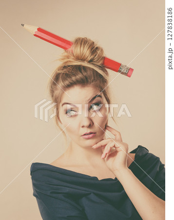 Thinking blonde woman having big pencil in hair 127838186