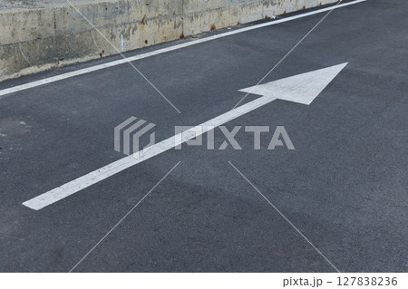 A large white arrow points straight ahead on a asphalt road 127838236