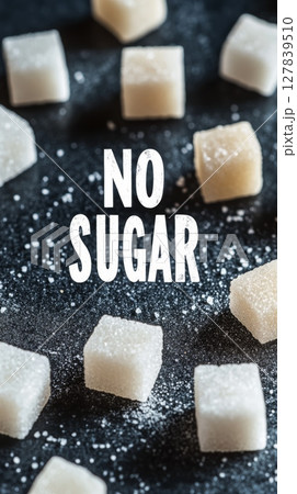 White sugar cubes scattered on a dark surface, with the text no sugar superimposed, promoting sugar reduction and a sugar free lifestyle for better health 127839510