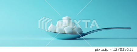 Spoon holding refined sugar cubes represents excessive sugar intake, raising awareness about sugar reduction, low sugar lifestyle, and the dangers of added sugar for a healthier diet 127839513