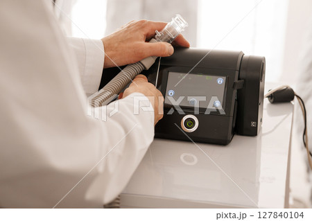 Medical CPAP Humidifier Setup: Doctor Connecting Hose to Sleep Apnea Machine on White Table, Healthcare Concept Medical CPAP Humidifier Setup: Doctor Connecting Hose to Sleep Apnea Machine on White Table, Healthcare Concept 127840104