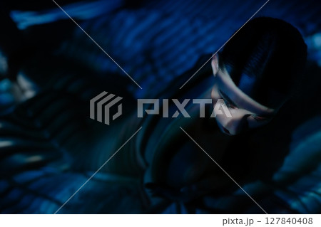 Woman illuminated by projector light creating artistic shadows indoors 127840408