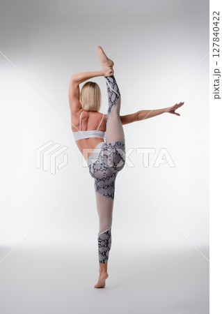 Woman demonstrating advanced yoga split pose in a studio setting 127840422