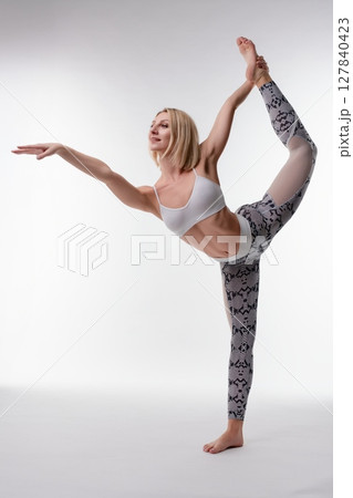 Woman performs an impressive yoga split pose in a studio environment Woman performs an impressive yoga split pose in a studio environment 127840423
