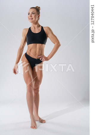 Strong woman showcasing fitness and confidence in minimal sportswear 127840441