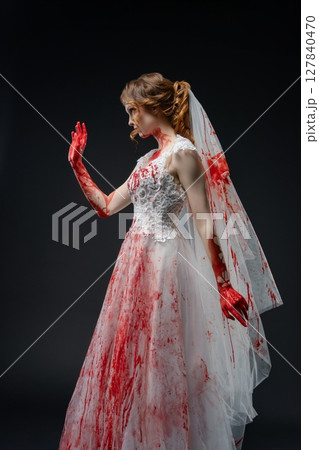 Bride in blood-stained lingerie holds katana in a dark, dramatic setting 127840470