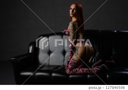 Sensual couple in intimate lingerie pose on black couch in dim lighting 127840506