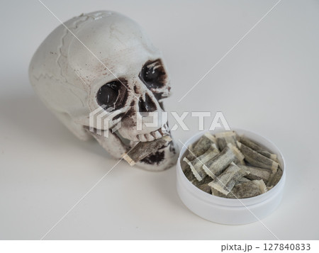 Skull Chewing Tobacco on a White Table. 127840833