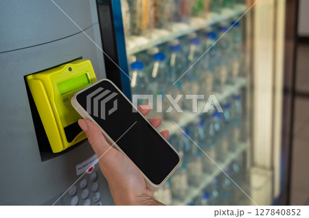 Modern Vending Machine Payment With Mobile Phone. A woman buys a bottle of water from a self-service machine.  127840852