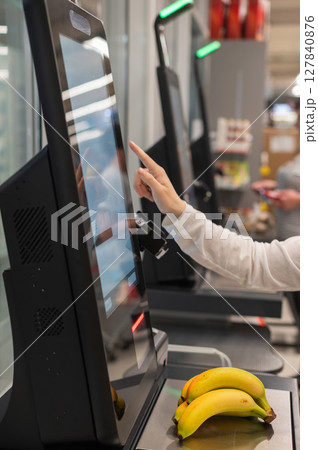 Faceless woman using self-checkout technology at grocery store. Faceless woman using self-checkout technology at grocery store. 127840876