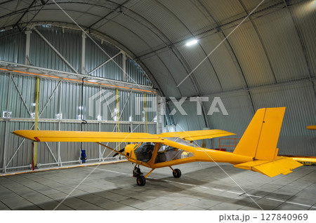 Yellow airplane glider in the hangar.  127840969