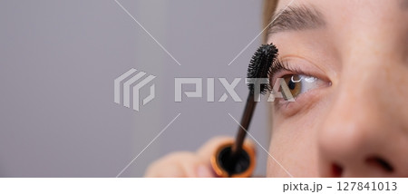 Young Woman Applying Mascara to Enhance Eyelashes.  127841013