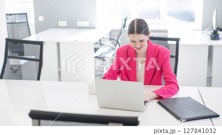 Caucasian business woman in fuchsia jacket working at computer. Caucasian business woman in fuchsia jacket working at computer. 127841032