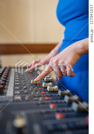 Hands Adjusting Sound Levels on Mixing Console.  127841037