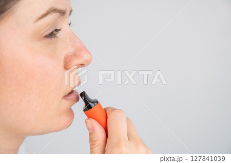 Caucasian woman smoking disposable vape.  127841039