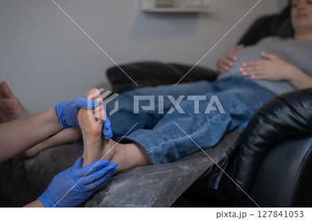 Pregnant woman getting professional foot massage. 127841053