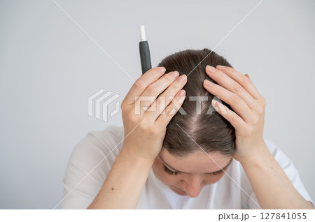 Tired woman smoking an electronic cigarette while working on a laptop. Tobacco heating system. Tired woman smoking an electronic cigarette while working on a laptop. Tobacco heating system. 127841055
