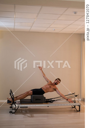 A man doing Pilates on a reformer.  127841070