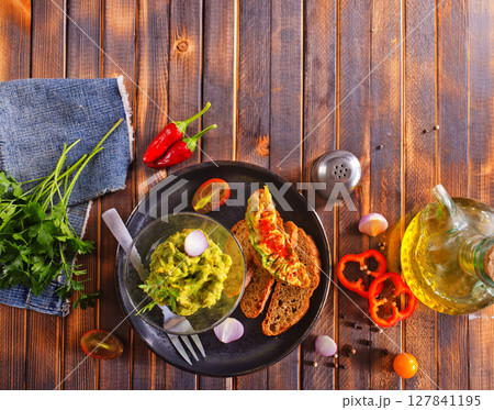 Traditional Mexican Dip Sauce Guacamole in a bowl with bread toasts 127841195