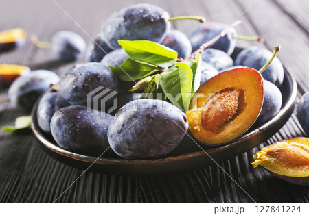 Ripe plum on dark wooden background Ripe plum on dark wooden background 127841224