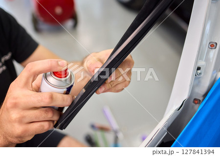 Applying spray lubricant to car door hinges helps keep them functioning smoothly Applying spray lubricant to car door hinges helps keep them functioning smoothly 127841394