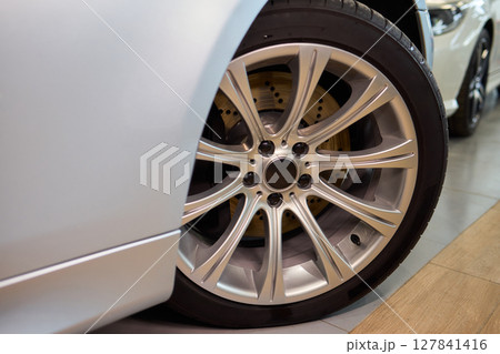 Detailed shot of a sleek black and silver alloy wheel on a motor vehicle 127841416