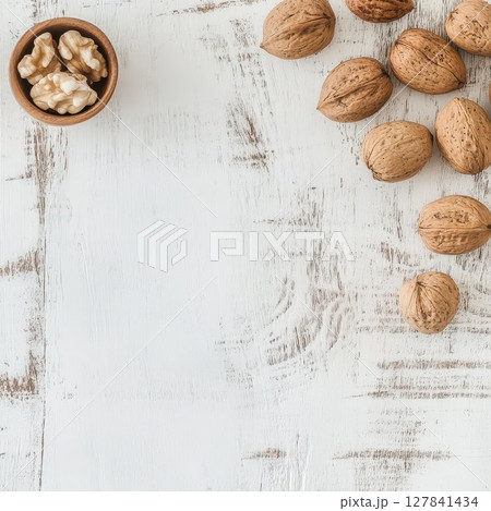 Nuts arranged on a wooden table with a bowl 127841434